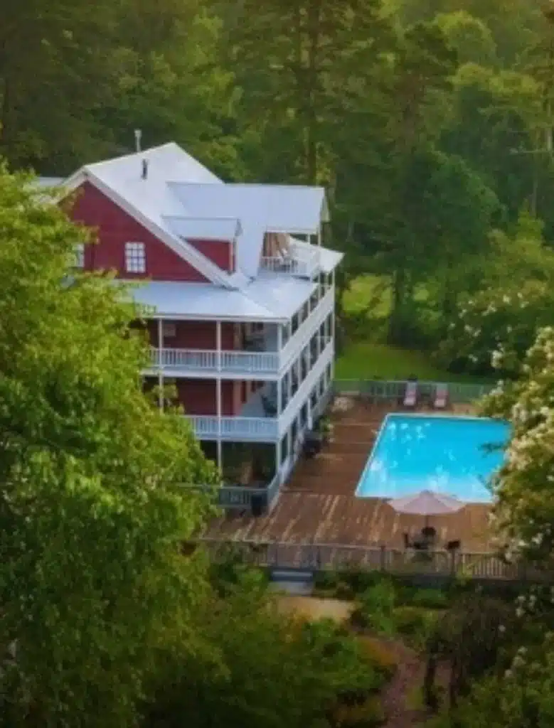 A Wellness Retreat in the North Georgia Mountains That Changes Everything 4 Glen-Ella Springs Inn with wraparound porches and pool surrounded by green mountain forest
